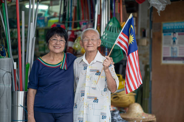 Asian Chinese senior owner Waving Malaysian Flags in front shop stock photo