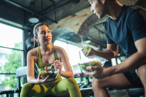 wo Asian people healthy eating salad after exercise at fitness gym. stock photo