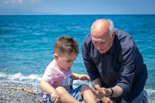 A grandson and his grandfather playing with some rocks on the beach