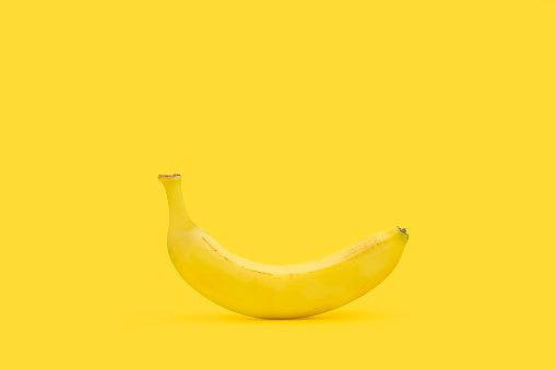 A banana on a yellow background with copy space