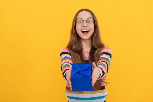 istock happy child in eyeglasses giving present box for holiday, purchase 1423999981