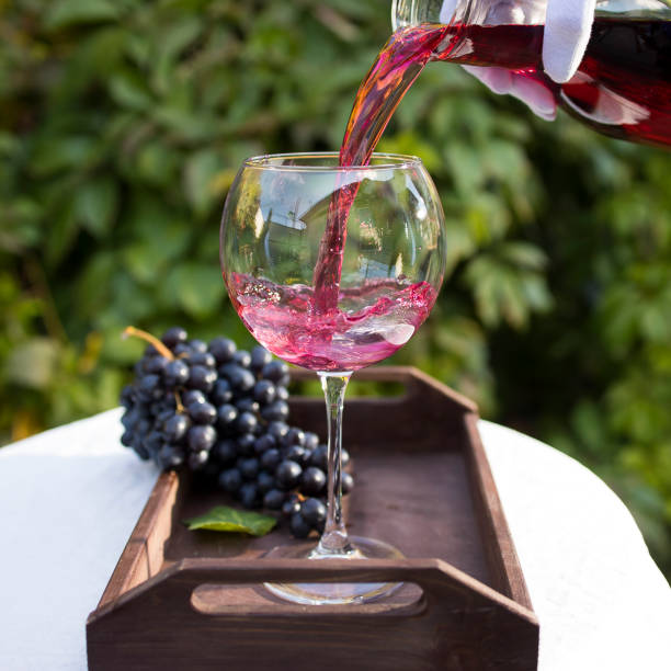 kieliszek czerwonego wina przygotowany do degustacji stoi na stole z białym obrusem na zewnątrz w słońcu - wine decanter red restaurant zdjęcia i obrazy z banku zdjęć