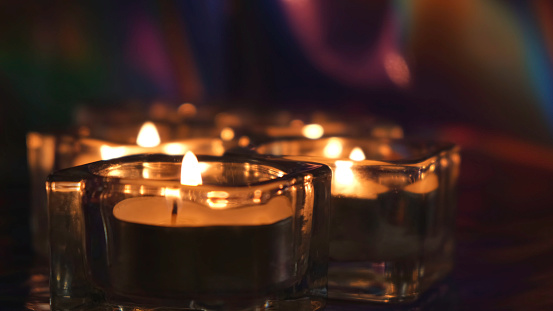 Burning candles on table in the darkness. Close up of small candles in glass candlesticks standing on the table in dark room creating romantic atmosphere for date.