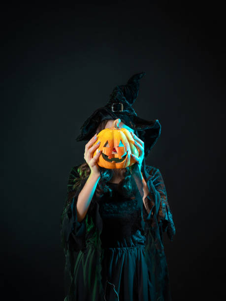 istock beautiful witch in a pointed hat Holding a pumpkin with a laughing face, 1424001622