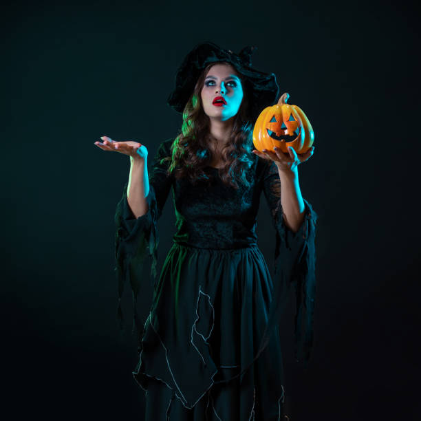 istock A young beautiful witch in a conical hat holds a Halloween pumpkin in her hands 1424001626