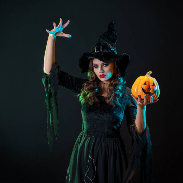 istock A young beautiful witch in a conical hat holds a Halloween pumpkin in her hands 1424001634