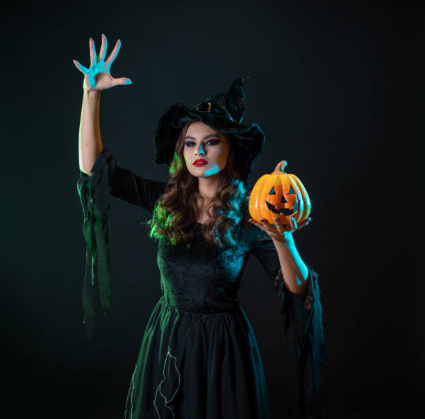 istock A young beautiful witch in a conical hat holds a Halloween pumpkin in her hands 1424001635