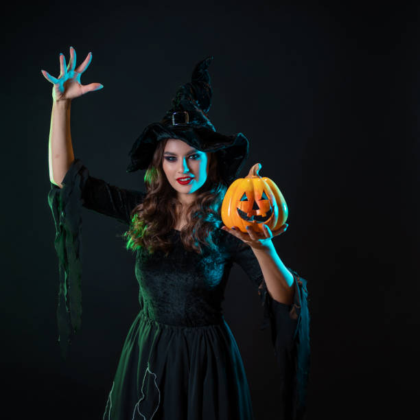 istock A young beautiful witch in a conical hat holds a Halloween pumpkin in her hands 1424001637