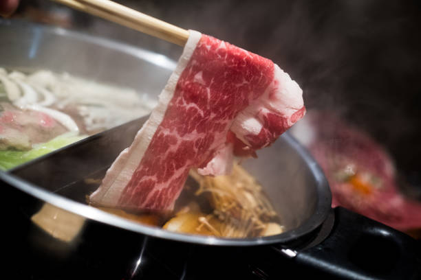 istock Hand using chopsticks pick premium raw beef sliced beef over the hot pot soup for Shabu Shabu 1424002446
