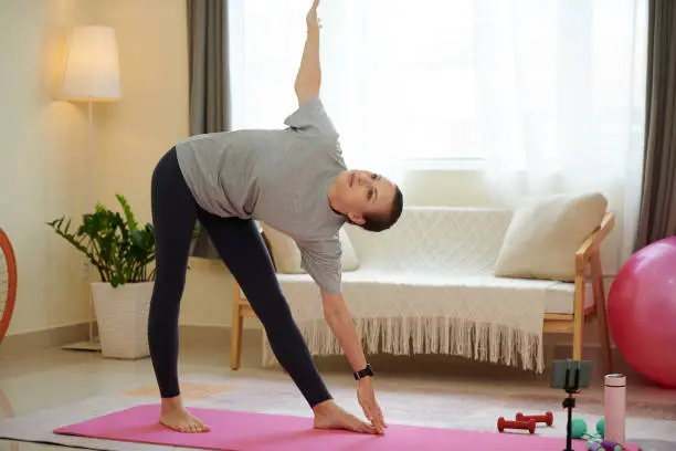 Woman practicing triangle yoga pose when working out at home