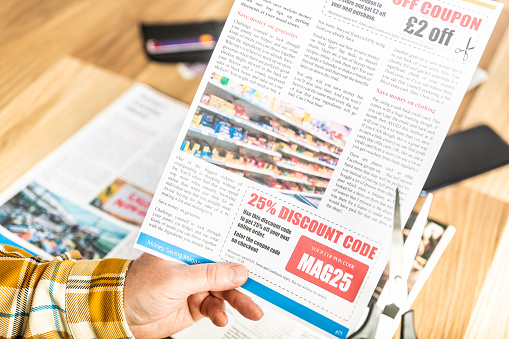 Cutting out a money saving discount coupon from a magazine