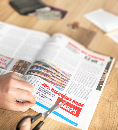 Cutting out a money saving discount coupon from a magazine