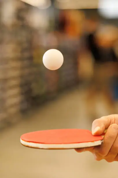 Photo of a ball in flight over a table tennis racket in the player's hand