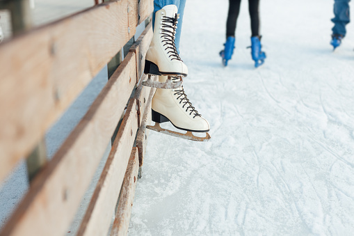 Close-up of woman legs in white ice skates with copy space