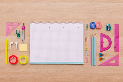 Back to school concept, creative layout with various school supplies, pencils, ruler, tapes, notebook, paper clips, pencil sharpener, notepads, markers  on wooden background with copy space