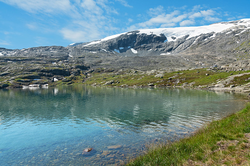 Blue lake landscape with snow covered mountain, Norway. Nibbevegen road to Dalsnibba mountain from Geiranger.