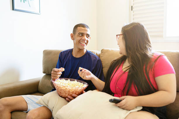 istock Friends sitting on the sofa eating popcorn and watching television 1424026489