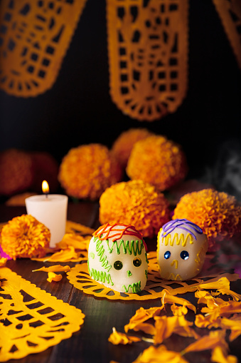 Sugar skulls with Candle, Cempasuchil flowers or Marigold and Papel Picado. Decoration traditionally used in altars for the celebration of the day of the dead in Mexico