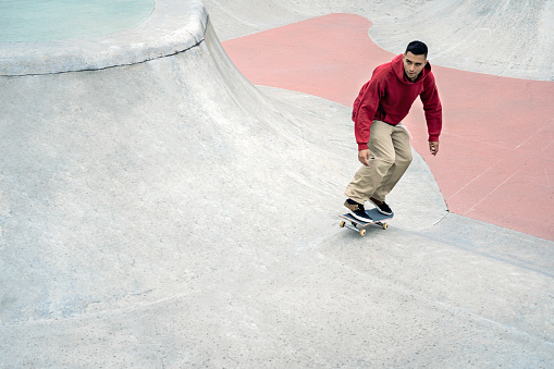 Young latino millennial riding a skateboard at the skatepark in the urban environment of the city of bogotá. Lifestyle and skate tricks.