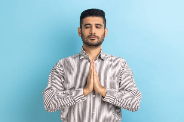 istock Relaxed young businessman with beard standing doing yoga meditating exercise, keeping palms together 1424031075