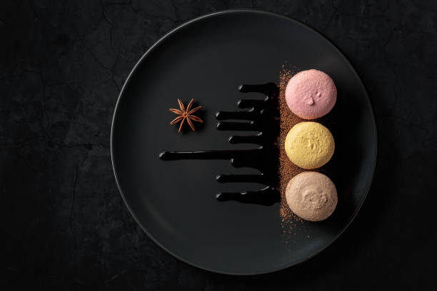istock Macaroons on a black plate garnished with chocolate sauce and cocoa powder. 1424032236