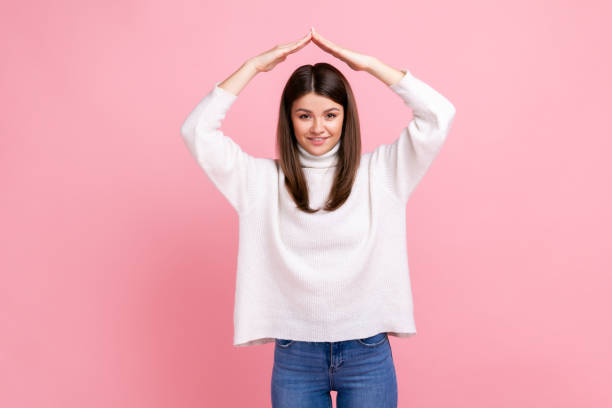 femme faisant le toit des mains au-dessus de la tête regardant la caméra avec un sourire denté, se sentant en sécurité - roof shape photos et images de collection