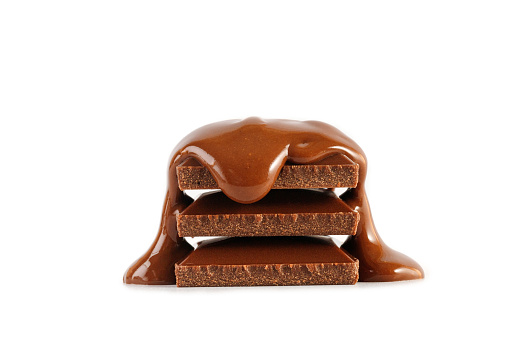 Stack of chocolate pieces bars with liquid melted chocolate isolated on a white background.