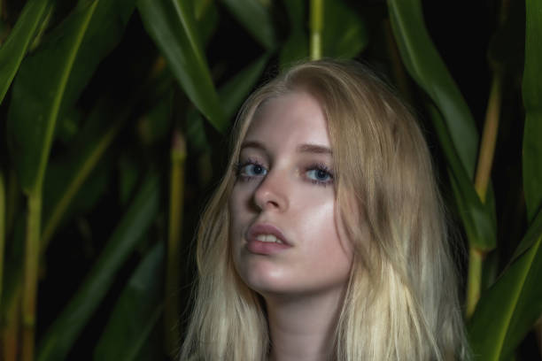 Blonde young woman poses outdoors closeup. Horizontally.