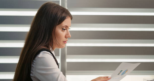 istock Calm focused woman working using paper documents sitting in the modern office. 1424043466