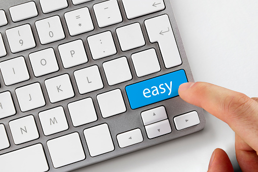 Human finger pushes blue easy button on computer keyboard