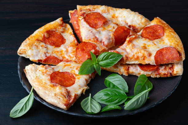 istock Delicious pepperoni pizza and basil on dark background 1424058736