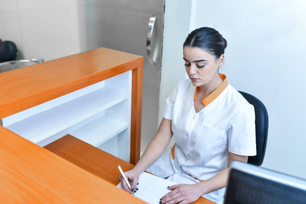 istock Beautiful Nurse Making Appointments In Dental Clinic Lobby 1424059446