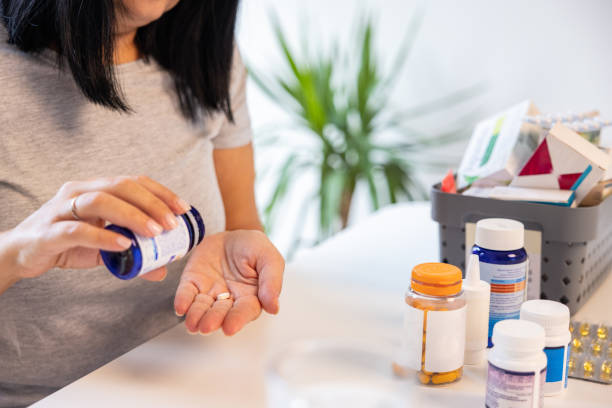 istock Unrecognizable woman taking a pill from a pill bottle 1424065908