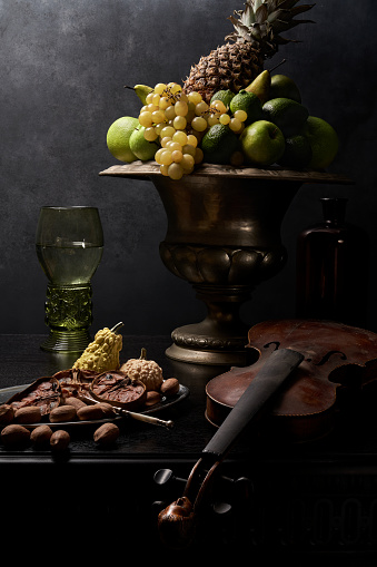 Still life with antique table, green fruit in silver bowl,  nuts, Renaissance  Roemer glass goblet. Dutch masters oil painting style.  Very detailed and sharp photography