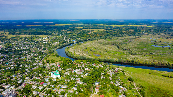 Aerial view of a small city on a beautiful summer day with a green landscape behind it. Picture from the drone of the village on a sunny day. Summer rural landscape from the top aerial view.