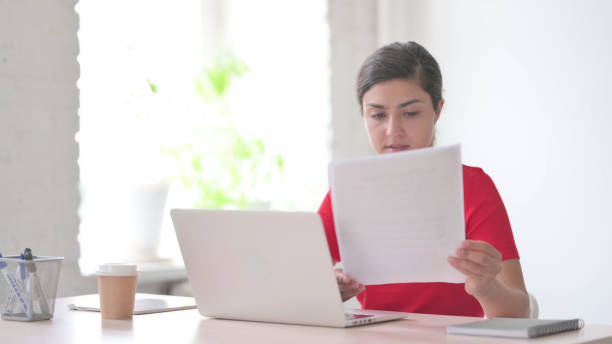 istock Paperwork by Indian Woman Working on Laptop in Office 1424079770