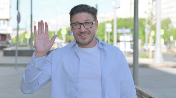 istock Welcoming Man Waving Hand for Hello Outdoor 1424095056