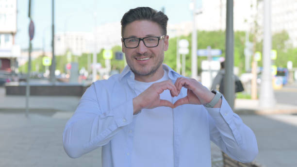 istock Loving Man showing Heart Shape by Hands Outdoor 1424095657
