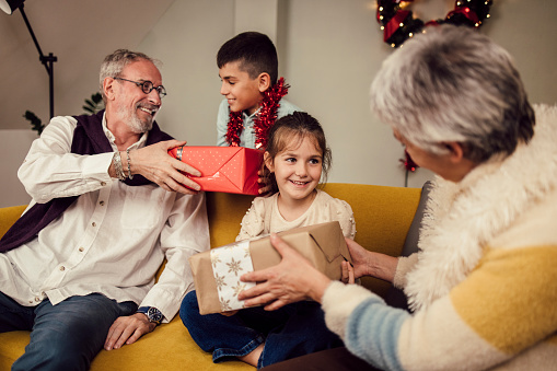 Grandparents giving presents for New Year's Eve to their two grandchildren.