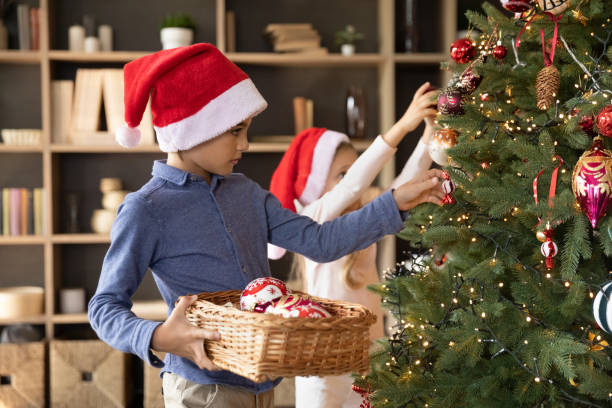 istock Two sibling kids in red Santa hats decorating fir tree 1424097682