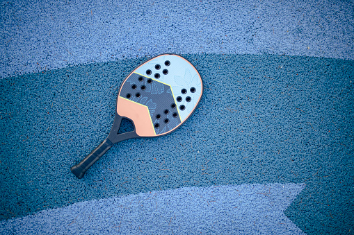 Close-up of a pickle ball racket on blue background