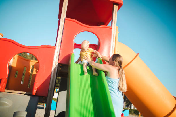 istock A mother helps her son down the slide 1424099550