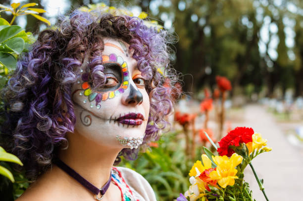 porträt einer jungen frau, die den friedhof mit la calavera catrina make-up besucht - spooky cemetery single flower flower stock-fotos und bilder