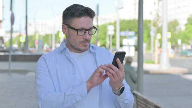istock Man Browsing Internet on Smartphone Outdoor 1424104923