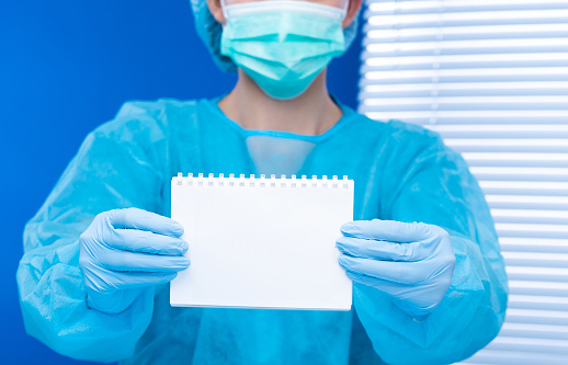 Surgeon doctor hold empty blank paper document. Medical person wear blue uniform glove mask in hospital to show responsibility ethic moral to social as professional healthcare, copy space