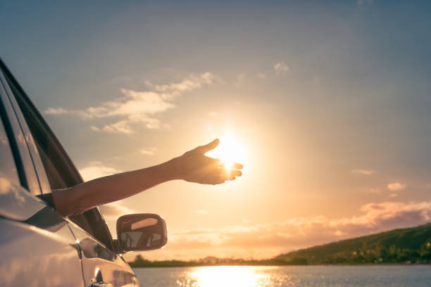 Happy woman in her car reaching out to the sky. stock photo