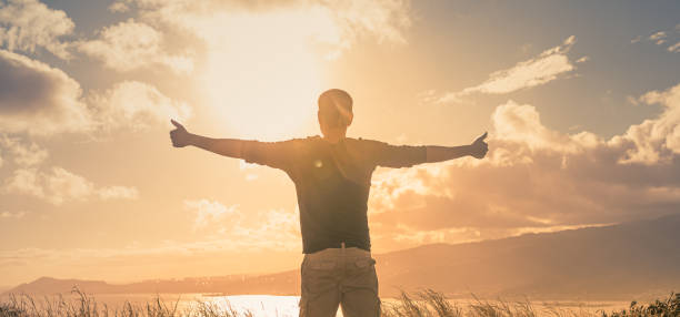 istock Young man standing on a mountain feeling happy and inspired. 1424123838