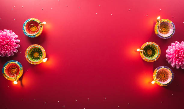 Happy Diwali - Clay Diya lamps lit during Diwali, Hindu festival of lights celebration. Colorful traditional oil lamp diya on red background Happy Diwali - Clay Diya lamps lit during Diwali, Hindu festival of lights celebration. Colorful traditional oil lamp diya on red background diwali stock pictures, royalty-free photos & images