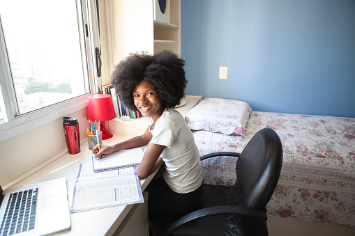 Teen girl studying at desk in bedroom