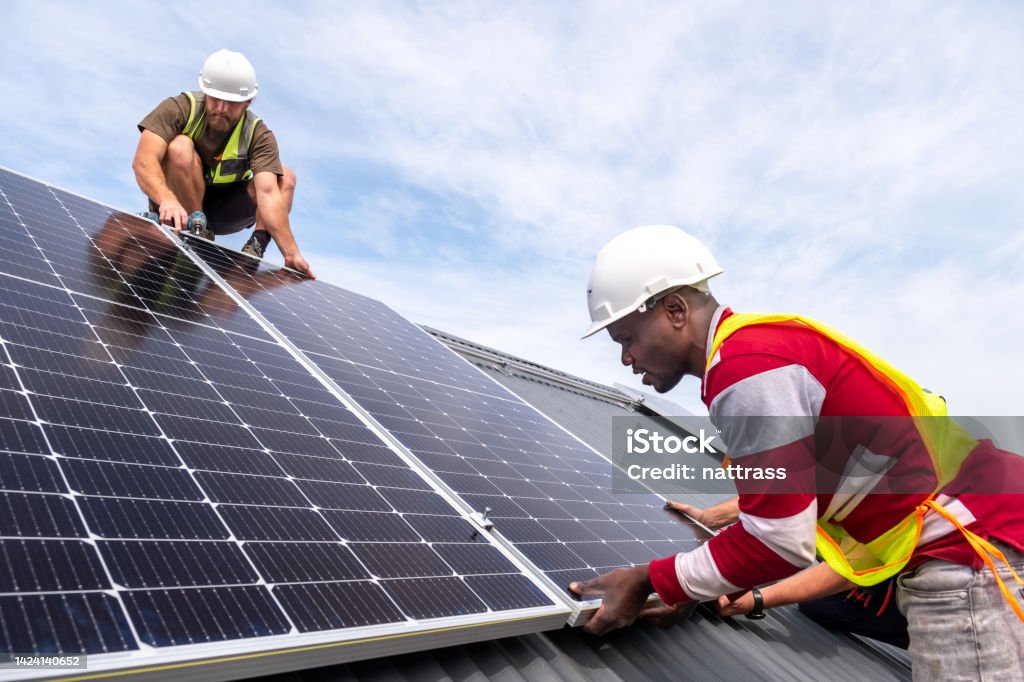 Installing a residential solar system Technicians carefully connect and install solar panels on a residential rooftop. Houses in South Africa installing solar energy solutions due to large scale load shedding. Renewable Energy Stock Photo